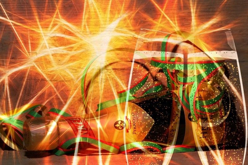 Champagnerflasche und Gläser mit bunten Luftschlangen und strahlenartigen Lichteffekten.