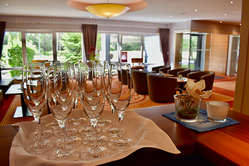 Innenraum eines eleganten Raumes mit einem Tisch voller leeren Sektgläser und einer Orchidee in einem kleinen Glas.