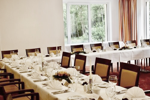 Elegant eingedeckter Tisch mit weißen Tischdecken und gefalteten Servietten in einem lichtdurchfluteten Raum.