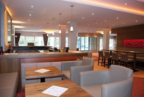 Moderner, gut beleuchteter Innenbereich einer Bar oder Lounge mit Holzmöbeln und Sitzgelegenheiten.