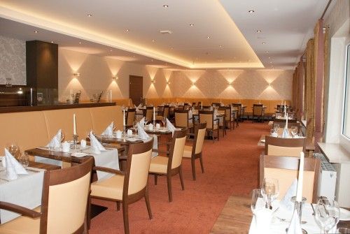 Elegantes Restaurant mit gedeckten Tischen, Stühlen und dezenter Beleuchtung.