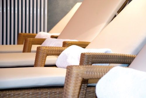 Reihen von gepolsterten Liegestühlen mit weißen Handtüchern in einem Entspannungsbereich.