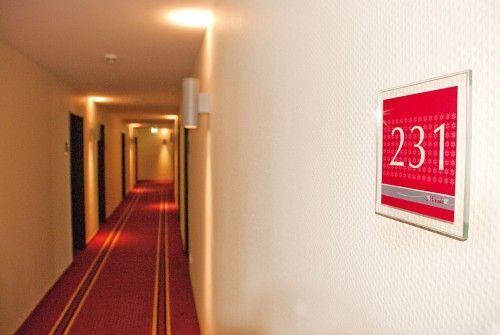Hotelkorridor mit rotem Teppich und einem Zimmernummernschild 231 an der Wand.