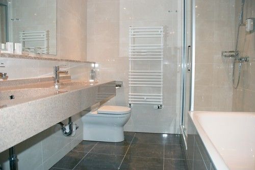Modernes Badezimmer mit großem Waschbecken, Toilette, Badewanne und Handtuchheizkörper
