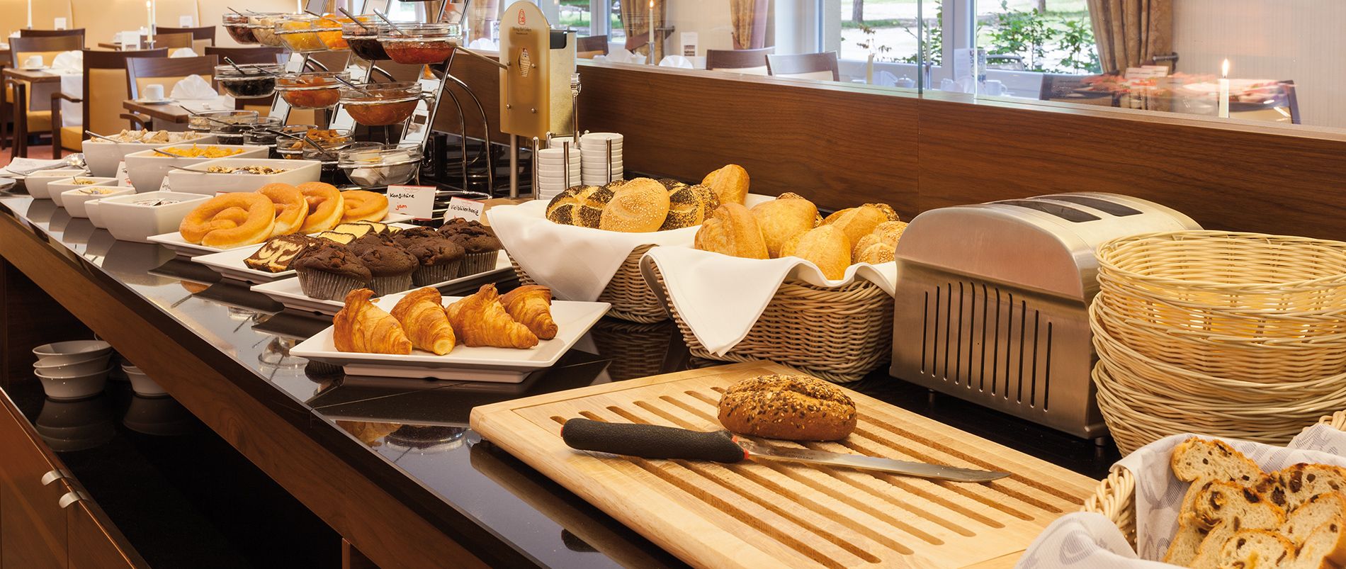Frühstücksbuffet mit Brot, Bagels, Croissants, Gebäck und einem Toaster.