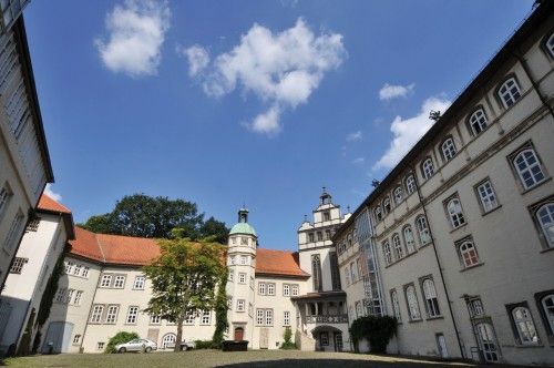 Innenhof eines historischen Gebäudes mit Turm und Satteldach.